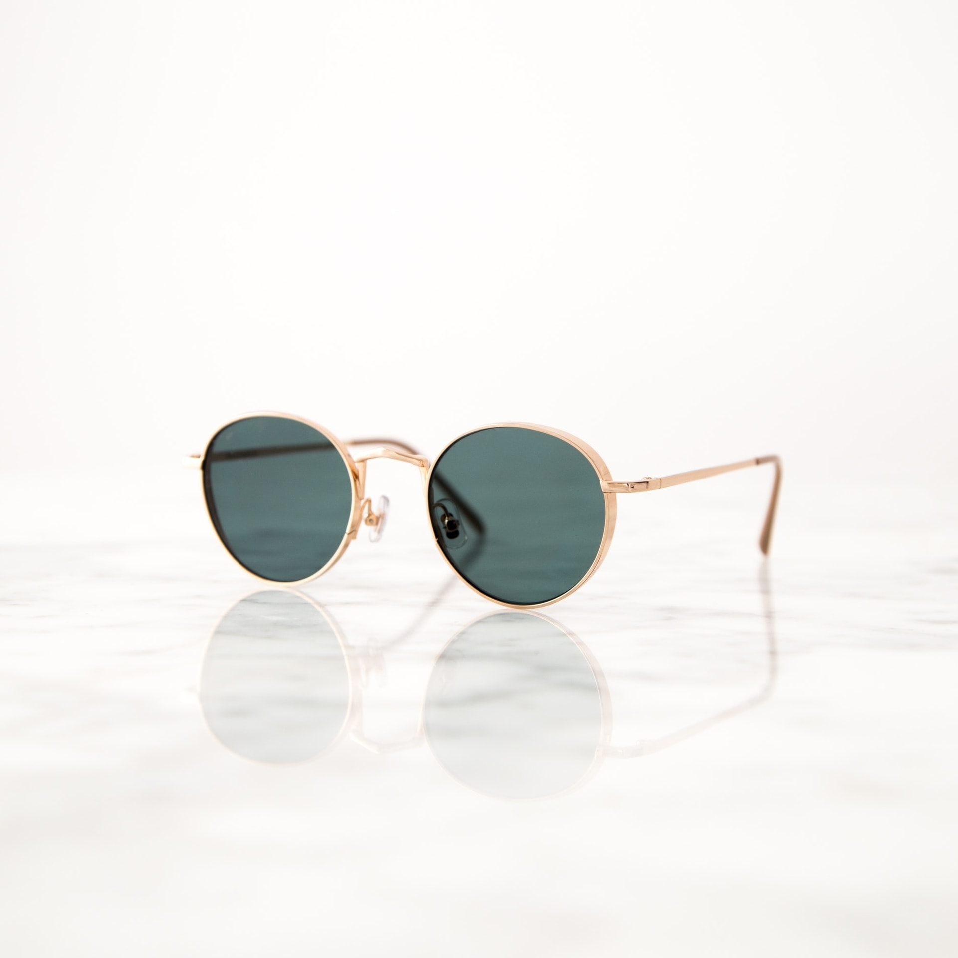 Sunglasses Gold frame sunglasses on reflective marble surface